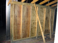 View of the framing of the outside wall. Note that the header has been further secured with lag bolts and washers. One of the metal roofing panels can be seen to the left.