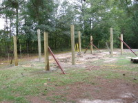 Viewed from the northeast.  The four corner posts for the outer walls of the side sections of the barn have been set in concrete, leveled, and braced.  These posts are eight-foot long six-by-sixes, set nominally 1.5 feet deep.